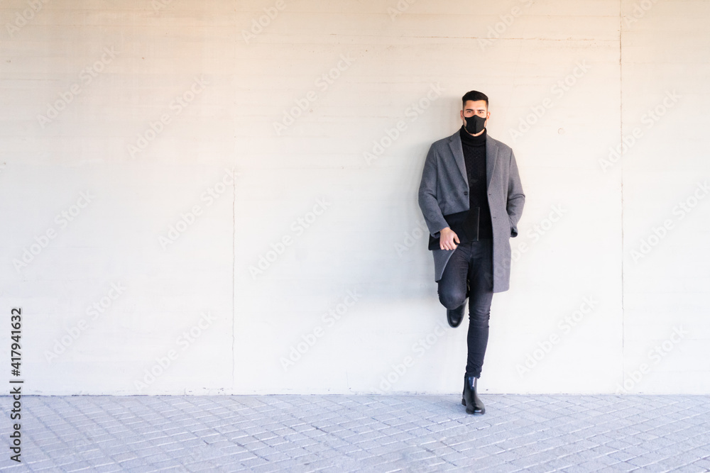 Young businessman with face mask leaning against a wall. Copy space. Young businessman with face mask leaning against a wall. Copy space.
