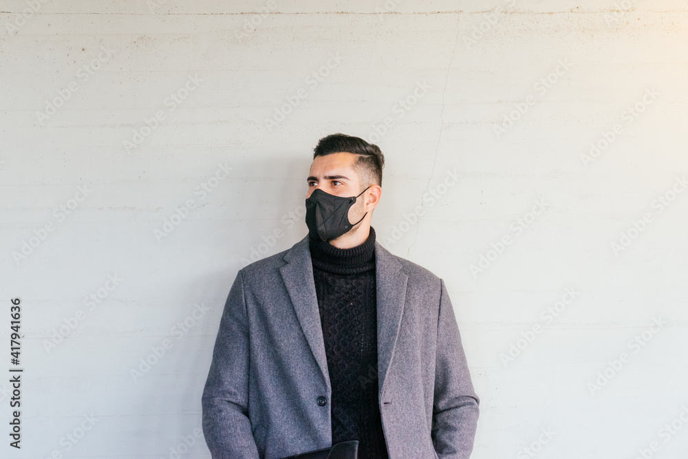 Portrait of a young businessman with face mask leaning against a wall. Portrait of a young businessman with face mask leaning against a wall.
