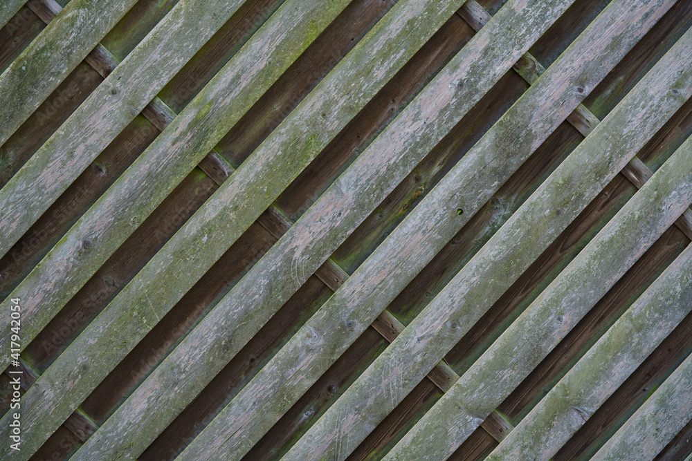 Fragment of a fence made of wooden planks diagonally. Shabby green color. Fragment of a fence made of wooden planks diagonally. Shabby green color.