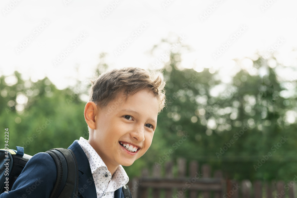 happy schoolboy, in a school uniform with a backpack on his back in the open air. First day of school. Back to school happy schoolboy, in a school uniform with a backpack on his back in the open air. First day of school. Back to school