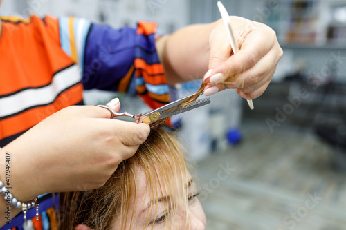 A hairdresser holds a pair of scissors and a comb. Woman getting a new haircut. Beauty treatments and hair care concept