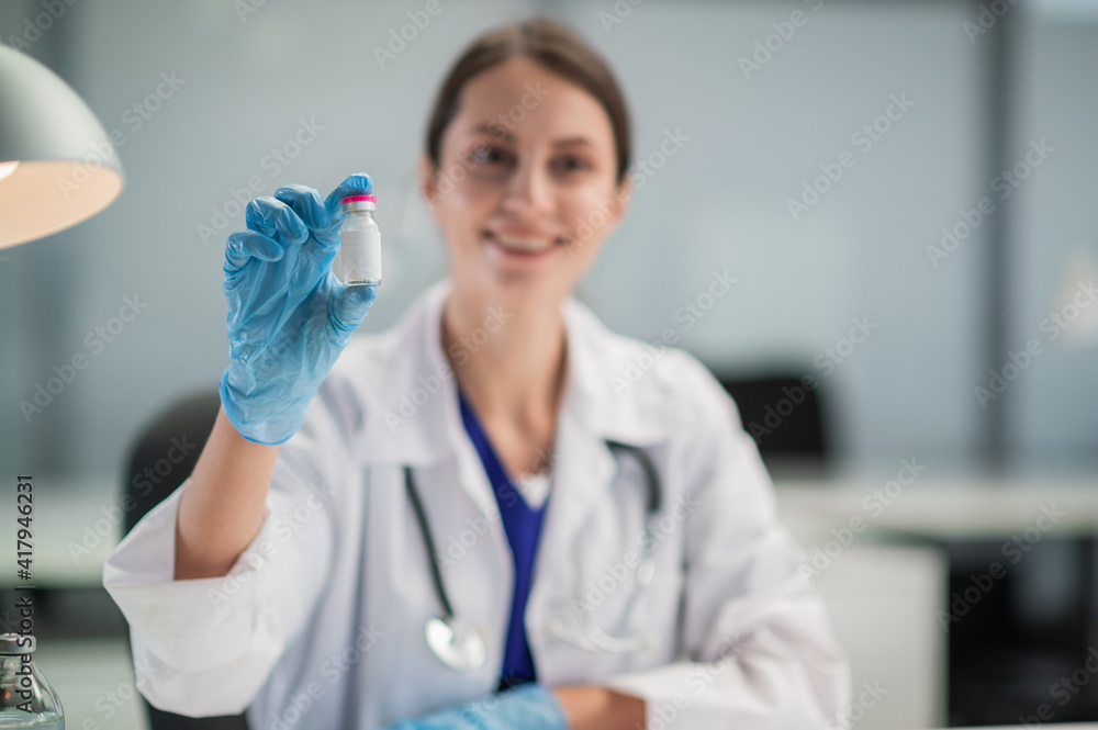 In the medical clinic, vaccination of the population against covid-19 has begun, the doctor shows a bottle with the vaccine. In the medical clinic, vaccination of the population against covid-19 has begun, the doctor shows a bottle with the vaccine.