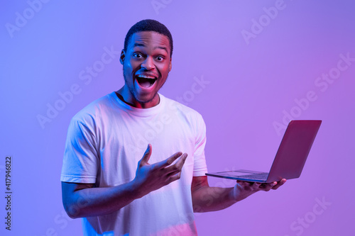 Cool Website. Excited Black Man With Laptop In Hands Under Neon Lighting