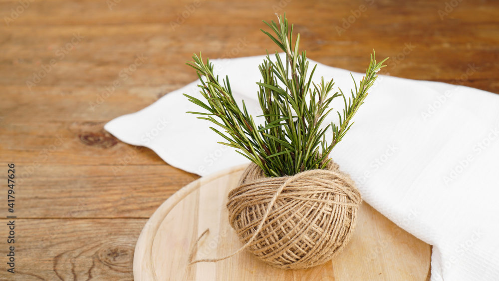 Sprigs of rosemary and skeins of jute rope on a wooden board for cutting. Rustic style. Spice Sprigs of rosemary and skeins of jute rope on a wooden board for cutting. Rustic style. Spice
