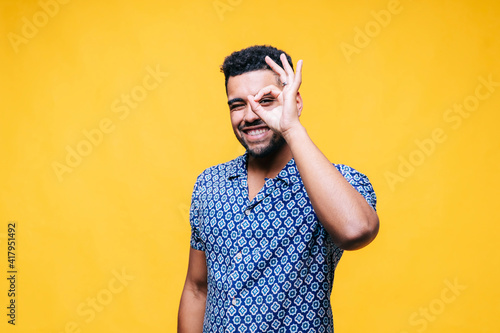 Happy man showing OK gesture while standing against yellow background photo
