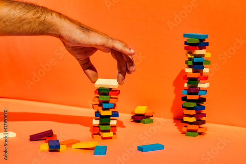 Man stacking toy blocks against orange background