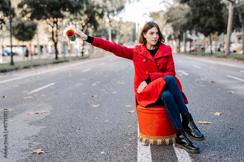 Young woman with attitude spilling coffee from cup on street photo