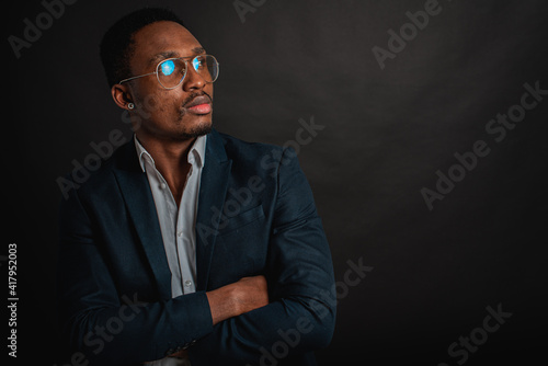 portrait of attractive, beautiful, serious and stylish professional African American businesswoman in dark suit and white shirt isolated on dark background. Low key. Selective focus