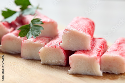 Appetizing crab sticks on wooden cutting board. Selective focus
