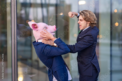 Male professional in fear while getting punched by colleague by glass wall photo