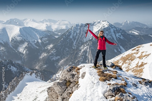 Woman hiker on a top of a mountain with pickax in hand. Success woman hiker. © Daniel Jędzura