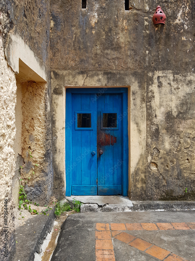closed blue door of an old building or house with a fragment of the floor, exit to the courtyard or street, a fragment of the facade