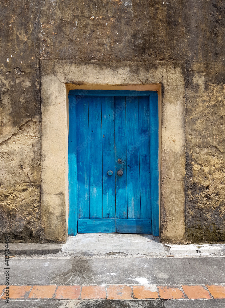 closed blue door of an old building or house with a fragment of the floor, exit to the courtyard or street, a fragment of the facade closed blue door of an old building or house with a fragment of the floor, exit to the courtyard or street, a fragment of the facade
