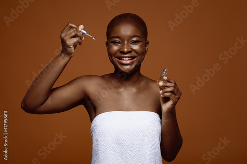 Skin Nutrition. Cheerful Attractive Black Woman Holding Bottle With Moisturizing Face Serum