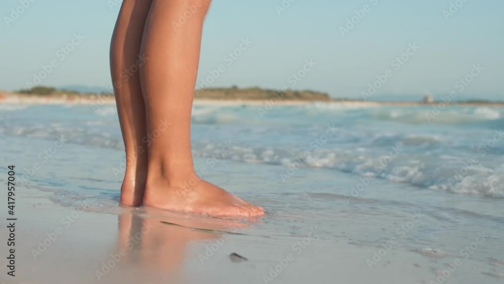 Sea waves rushing to woman legs at beach. Unknown girl standing at seashore. Sea waves rushing to woman legs at beach. Unknown girl standing at seashore.