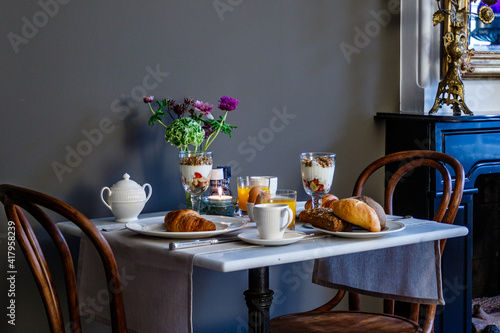 Breakfast table with a continental breakfast for two people against a grey wall