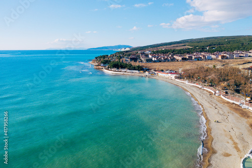 Fototapeta Naklejka Na Ścianę i Meble -  Aerial view of sea coast with sandy beach and small buildings. Beautiful blue and azure seascape from drone.