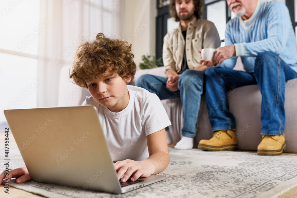 Children surfs on the web with a laptop at home with his family Children surfs on the web with a laptop at home with his family