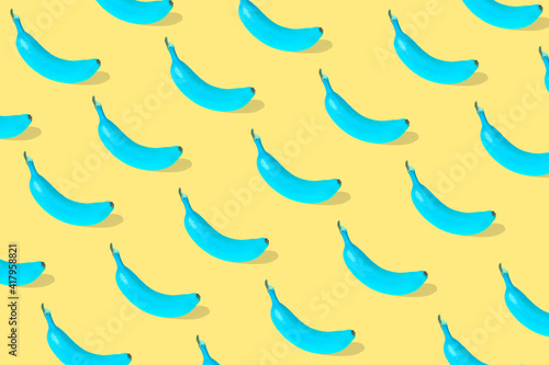 Trendy Summer pattern made with fresh banana fruit colored in blue on illuminating yellow background.