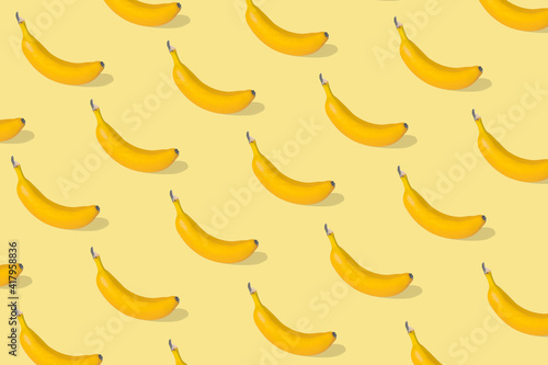 Trendy Summer pattern made with fresh banana fruit on illuminating yellow background.