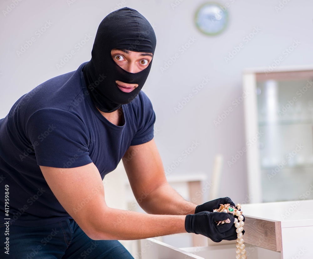 Robber wearing balaclava stealing valuable things Robber wearing balaclava stealing valuable things