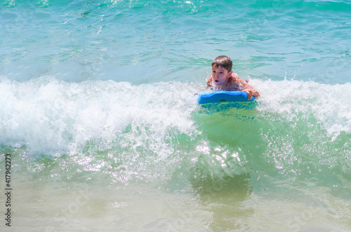 boy bodyboarding a wave on a turquoise water beach on a sunny summer day, bodysurfing, copy space © Javier