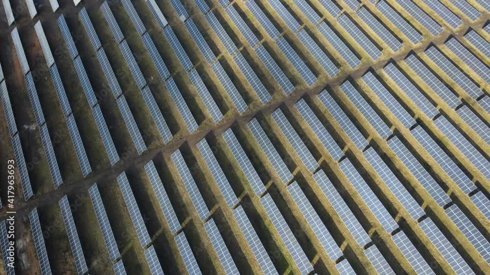 Solar power plant in a field on a sunny day. Bird's-eye. Solar panels are in the line in the field of energy production. A drone flies over a solar farm. Renewable green energy. Solar power plant in a field on a sunny day. Bird's-eye. Solar panels are in the line in the field of energy production. A drone flies over a solar farm. Renewable green energy.