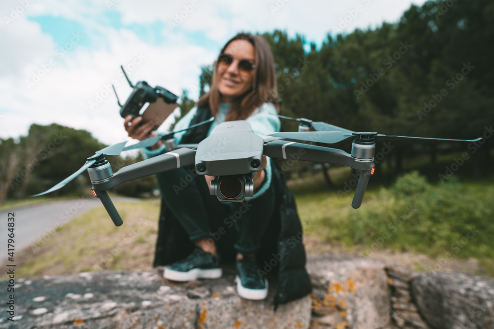 Fototapeta premium Young beautiful woman pilot with remote control ready to flying a drone