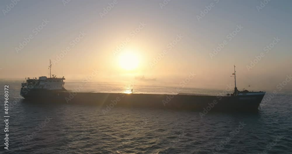Sea sunrise and sailing cargo ship in morning fog, spectacular aerial 4k video Sea sunrise and sailing cargo ship in morning fog, spectacular aerial 4k video