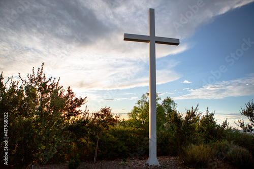 Sunlight bursts behind a mountain top cross of Jesus during golden hour at sunrise on Easter Morning 05