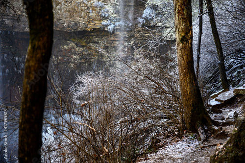 Ice coated shrubery and and rocks near a waterfall in a forest. photo