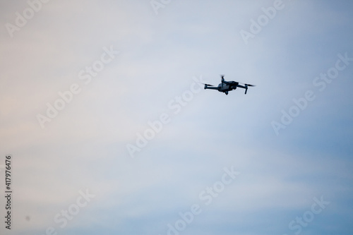 Small unregistered consumer drone flying. These kind of small quadcoper drones don't need license to be operated, as they are light and meant for beginners, amateurs and enthusiasts photo