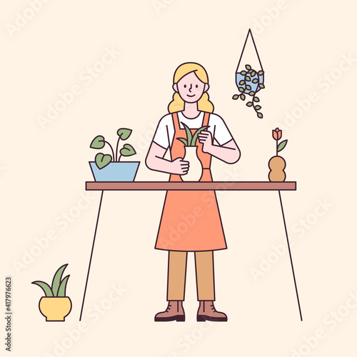 A woman is doing home gardening on the table. flat design style minimal vector illustration.