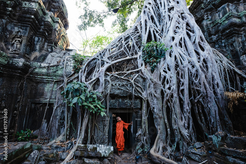 Buddhist monk under famous tree root temple, Angkor, Cambodia photo