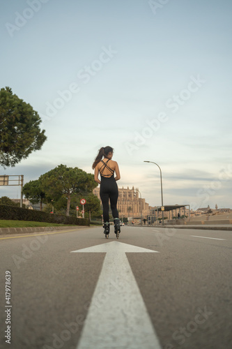 Caucasian girl on roller skates standing on the road on the promenade of Palma de Mallorca at sunset with the Cathedral Basilica of Santa Maria in the background, Spain (Perfect for copyspace) © Alberto Case