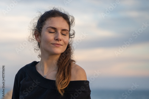 Caucasian girl with her eyes closed enjoying the sun and the sunset on the promenade in Palma de Mallorca, Spain (Perfect for copyspace)