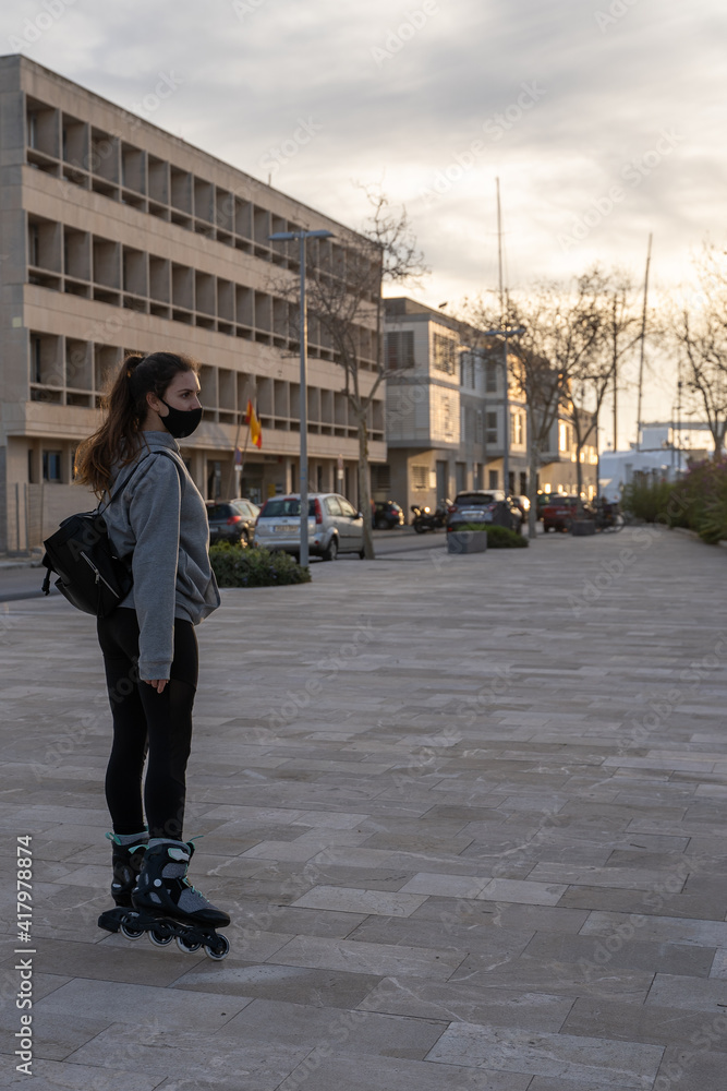 Girl looking at the horizon with skates on the seafront promenade in Palma de Mallorca, Spain