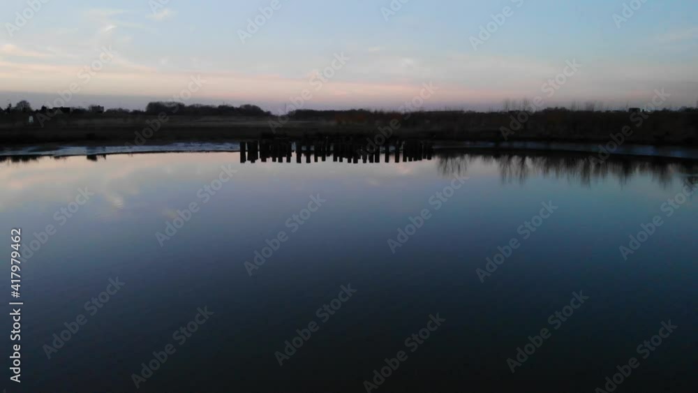 Wooden Pillars Reflected On Quiet River At Dusk In Crezeepolder Near The Village Of Ridderkerk In The Netherlands. - Aerial Drone Shot Wooden Pillars Reflected On Quiet River At Dusk In Crezeepolder Near The Village Of Ridderkerk In The Netherlands. - Aerial Drone Shot