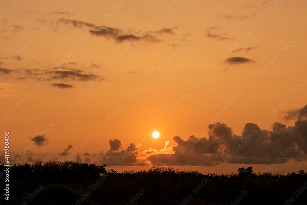 Beautiful dawn with the sun rising in orange colors and beautiful clouds composing the scene. Iriomote Island.