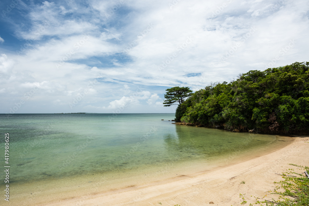 Typical tropical island calm beach on a cloudy day. Clouds and green vegetation.