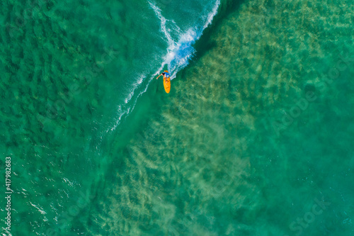 Surfer from above clean water riding waves