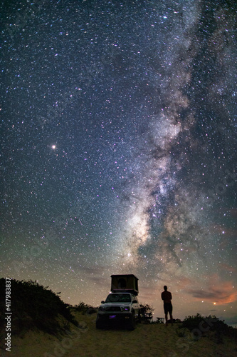 overland truck camper on beach illuminated Milky Way