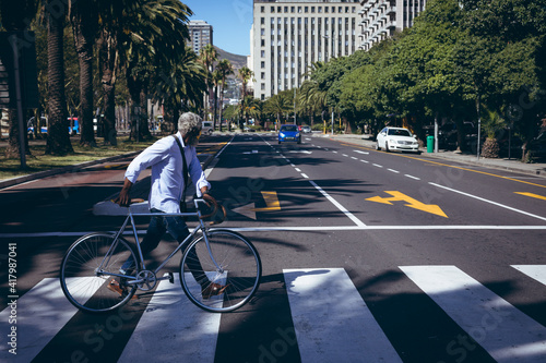 African american senior man wheeling bicycle across road on a pedestrian crossing photo