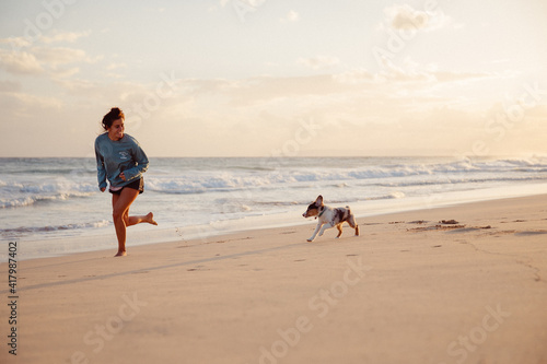 Australian Shepherd puppy and owner play on the beach