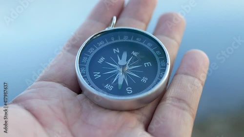 Close up of hand holding a compass over nature background for journey. Lifestyle and Vacation concepts. photo