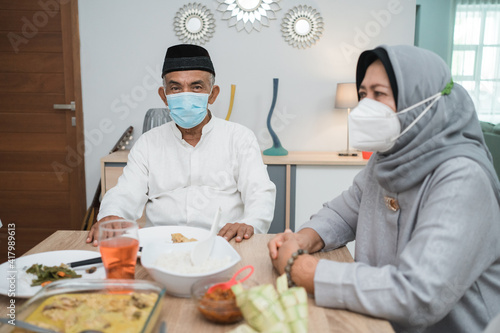 portrait of happy family muslim wear mask during eid mubarak celebration at home
