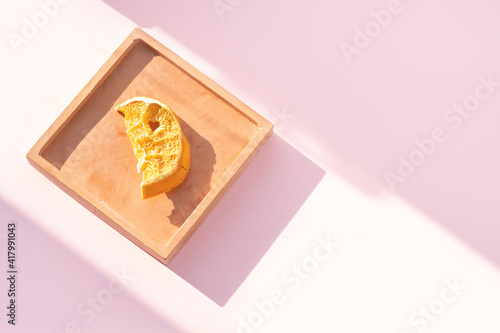 Dried oranges in light brown plate on pink background. Close-up of orange slices on a plate