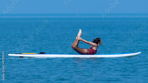 Sport woman yogini posing balancing table top practice yoga exercise on sup board on the sea in relaxing day , yoga is meditation and healthy sport concept.