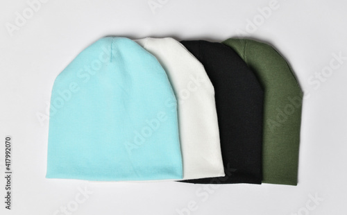 Set of four modern knitted beanie hats, green, black, white mint, light blue knitwear isolated on white background