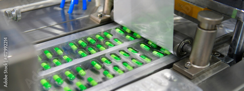 Fotografia, Obraz Green capsule medicine pill production line, Industrial pharmaceutical concept